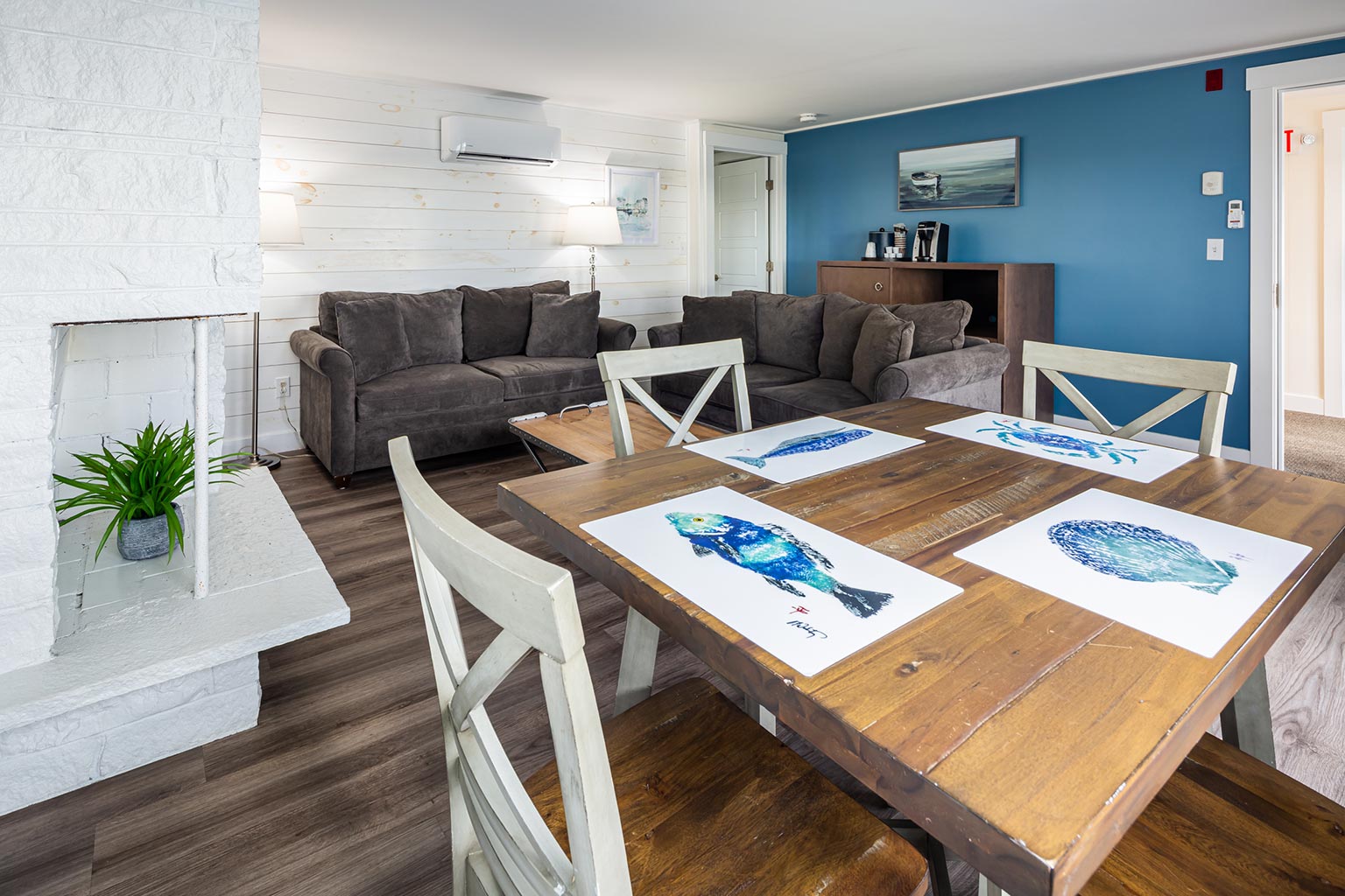 Breakwater Hotel Suite with couches in seating area, table and chairs in foreground.