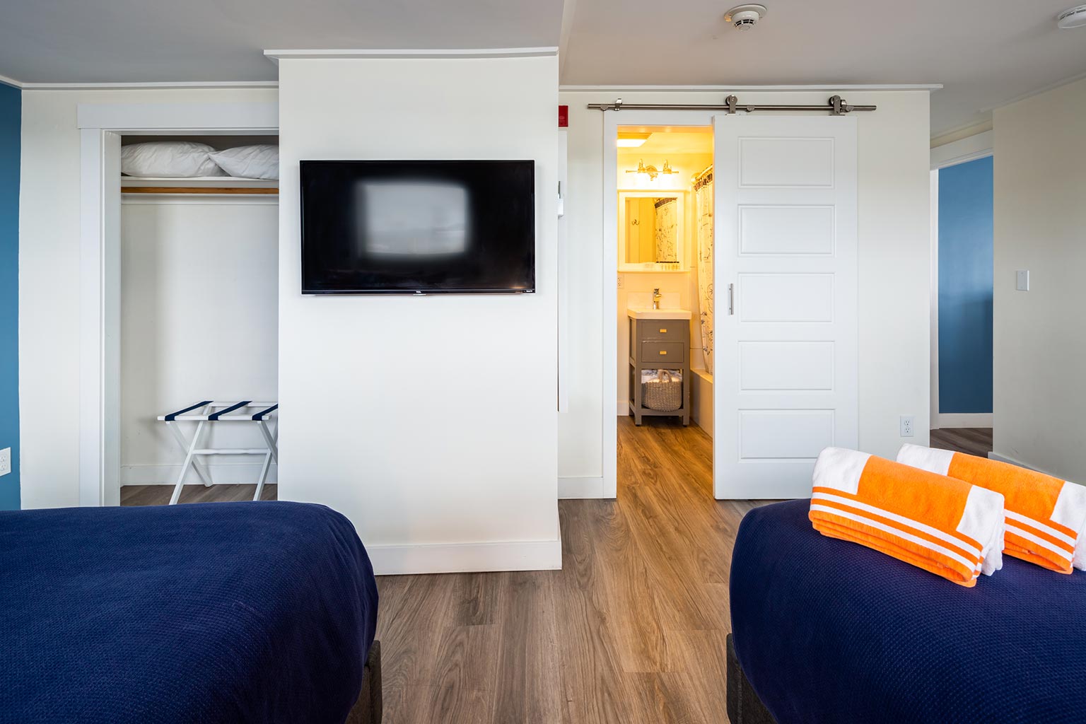 Hotel suite with two queen beds, closet area, and view into bathroom.