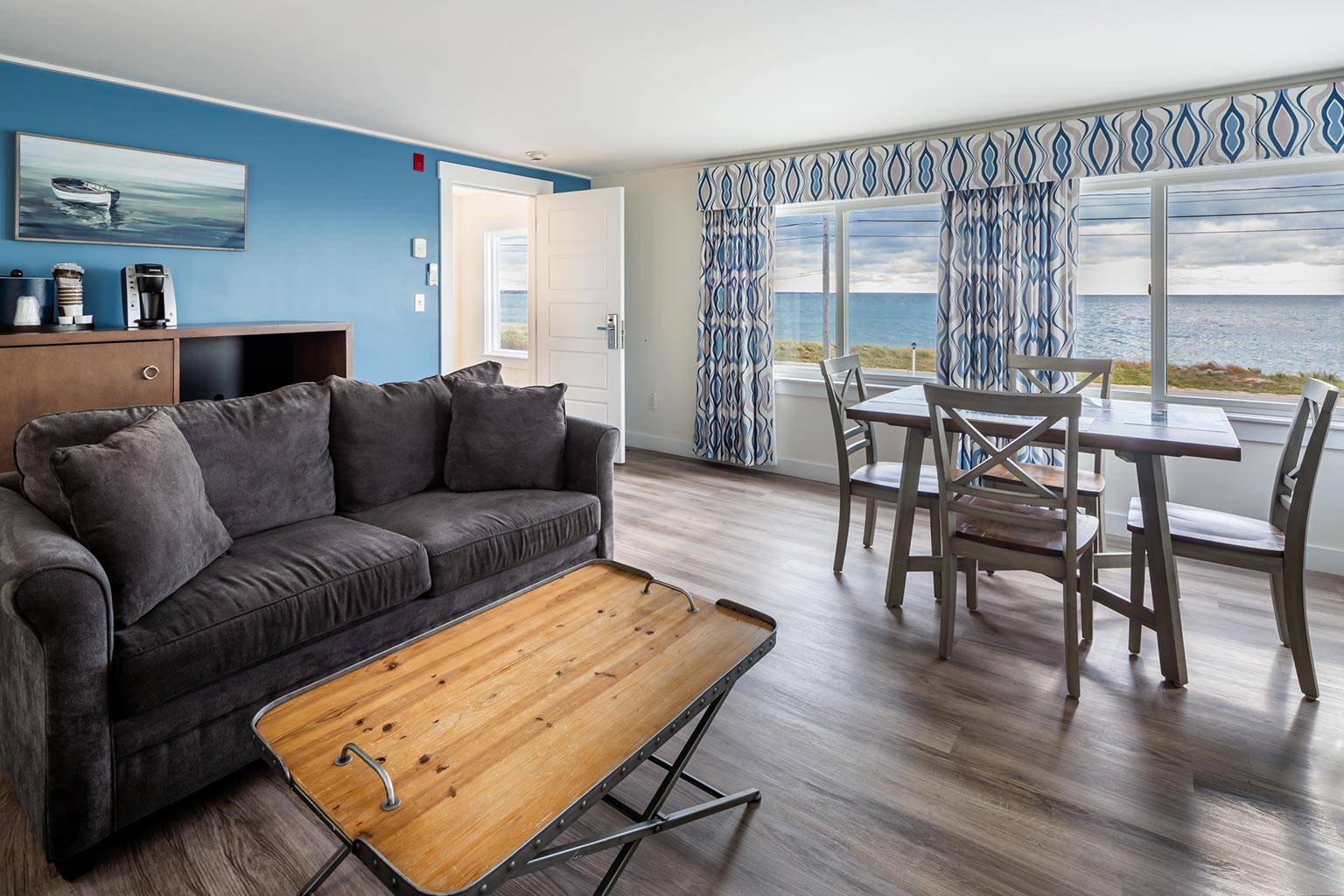 Hotel suite with couch seating area, table and chairs, and ocean view.