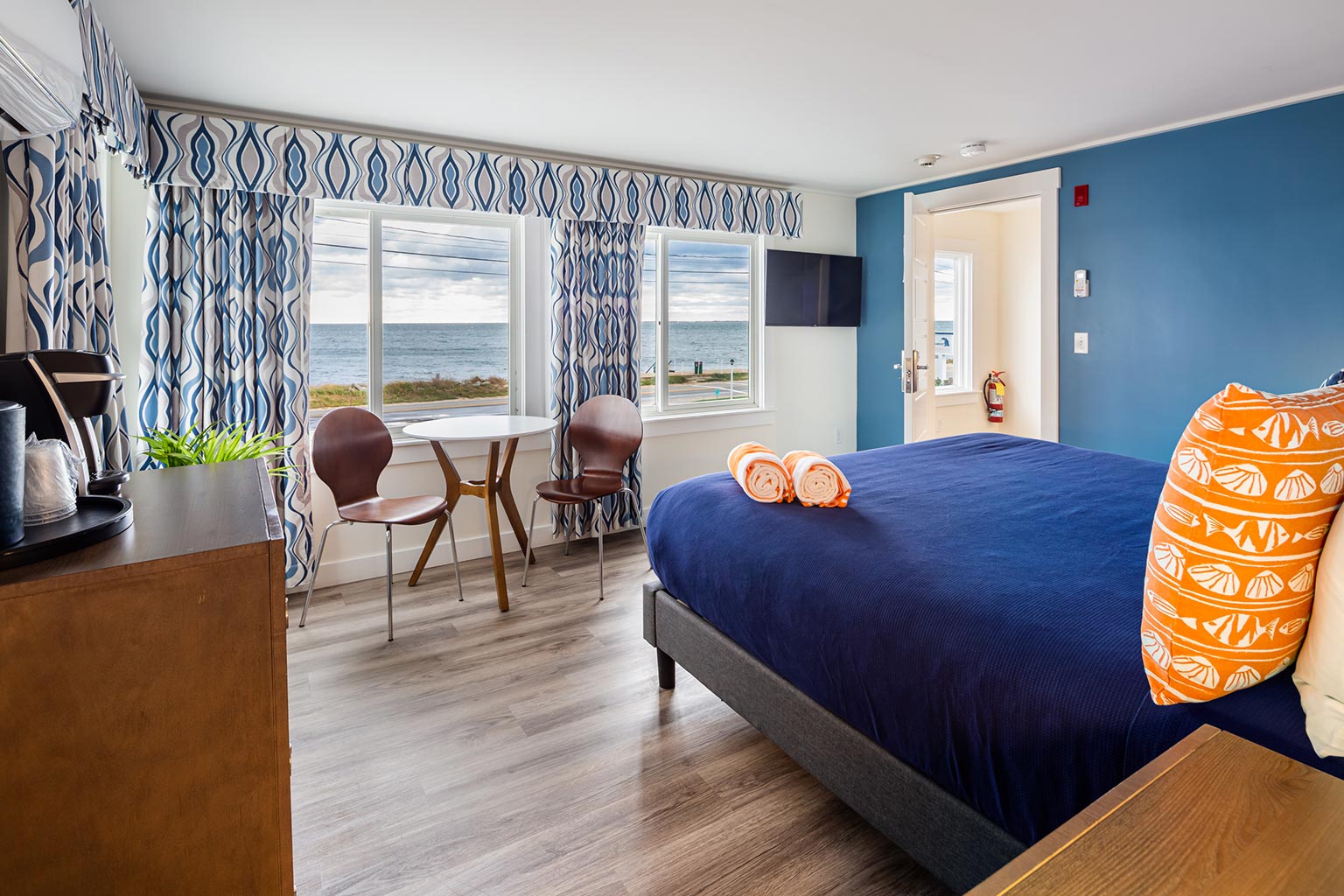 Breakwater hotel suite with king bed, chairs, table, ocean view