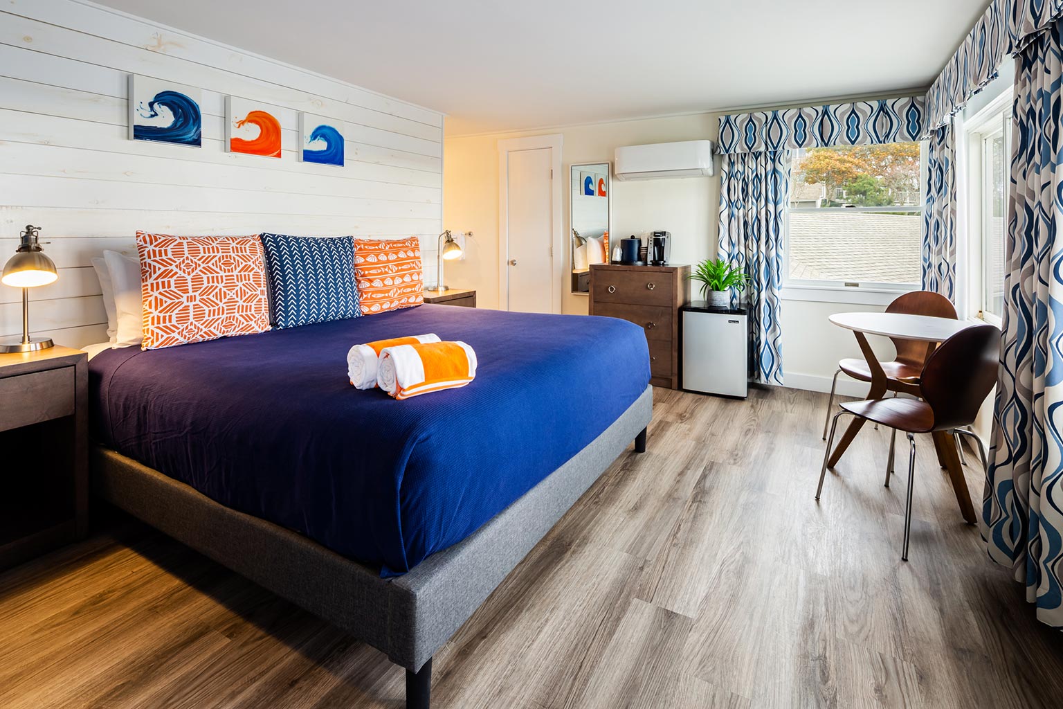 Breakwater hotel suite with bed, chairs, table.